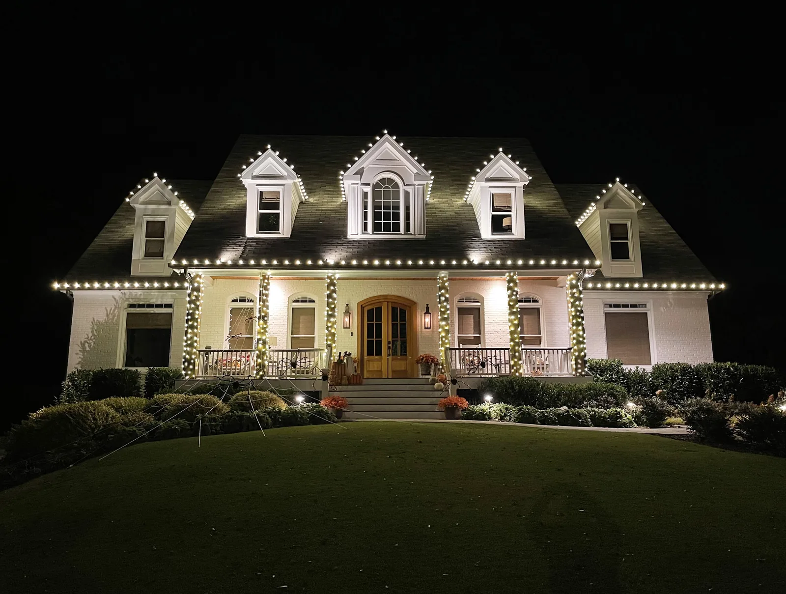 Cape Cod dormer Christmas light installation in Sandy Springs GA with wrapped porch columns and warm white roofline